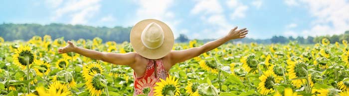 benefits happy woman with hat on in sunflower field